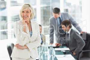 Mature businesswoman with colleagues discussing in office