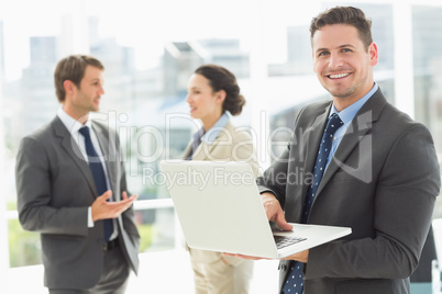 Businessman using laptop with colleagues discussing in office Businessman using laptop with colleagues discussing in office