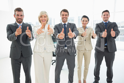 Confident business team gesturing thumbs up