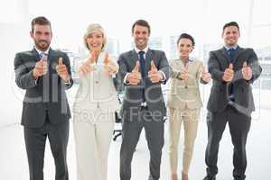 Confident business team gesturing thumbs up