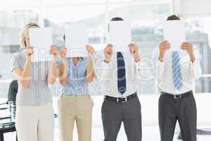 Business people with blank paper in front of faces in office