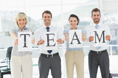 Happy business team holding papers indicating 'team'