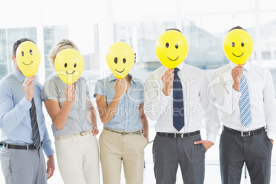 Business people holding happy smiles in front of faces