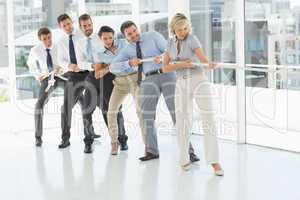 Group of business people pulling rope in office