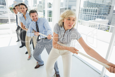 Group of business people pulling rope in office