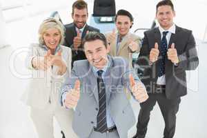 Confident business team gesturing thumbs up