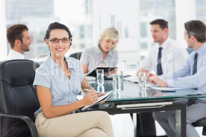 Businesswoman holding clipboard with colleagues discussing in of