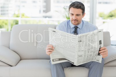 Well dressed man reading newspaper at home