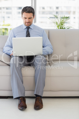 Well dressed man using laptop at home