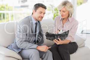 Smart businessman and his secretary  looking at diary on sofa