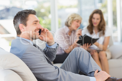 Businessman on call with female colleagues in background