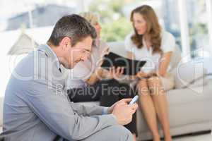 Businessman text messaging with colleagues sitting at home