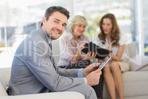 Businessman using digital tablet with colleagues at home