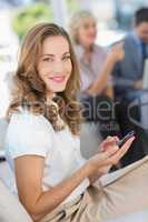 Businesswoman text messaging with colleagues using laptop