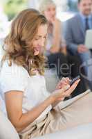 Businesswoman text messaging with colleagues using laptop