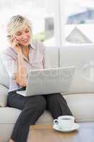 Businesswoman using mobile phone and laptop at home