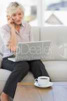 Woman using mobile phone and laptop at home