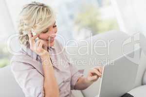Businesswoman using mobile phone and laptop
