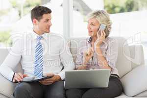 Businessman and his secretary with cellphone and laptop at home