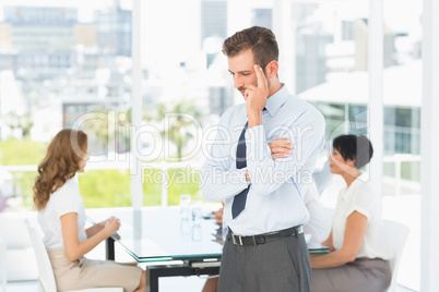 Thoughtful businessman with colleagues in meeting behind