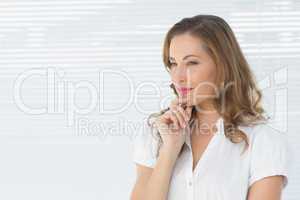 Thoughtful businesswoman looking away against blinds