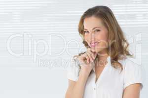 Smiling young businesswoman against blinds