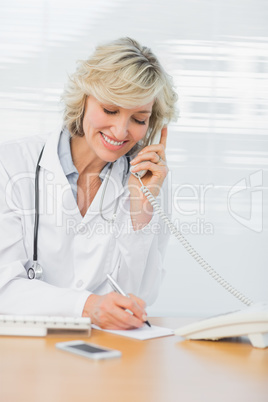 Doctor using phone while writing notes at medical office