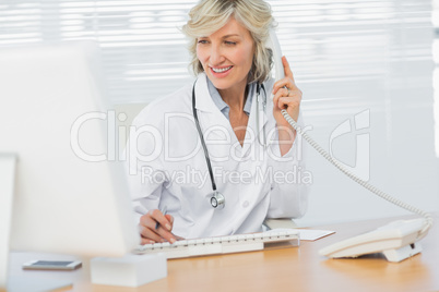 Doctor with computer using phone at medical office