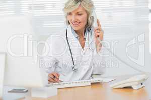 Doctor with computer using phone at medical office