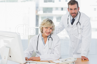 Smiling doctors with computer at medical office