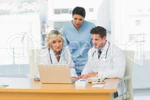Three concentrated doctors using laptop together