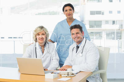 Smiling doctors with laptop at medical office
