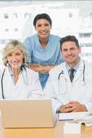 Smiling doctors with laptop at medical office