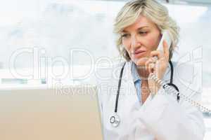 Doctor using laptop and phone in medical office