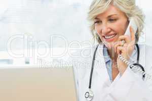 Female doctor using laptop and phone in medical office