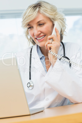 Female doctor using laptop and phone in medical office
