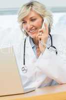 Female doctor using laptop and phone in medical office