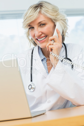 Smiling female doctor using laptop and phone