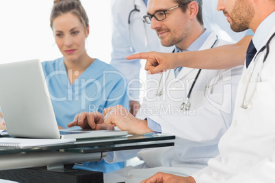 Group of concentrated doctors using laptop together