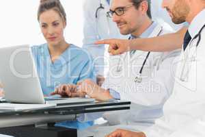 Group of concentrated doctors using laptop together