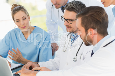 Group of concentrated doctors using laptop together