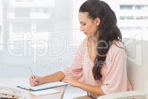 Concentrated businesswoman writing on clipboard