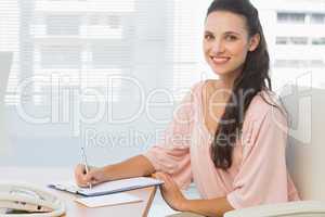 Businesswoman writing on clipboard at a bright office