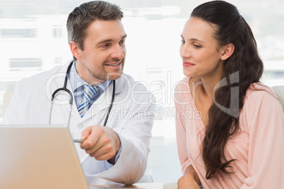 Male doctor showing something on laptop to patient