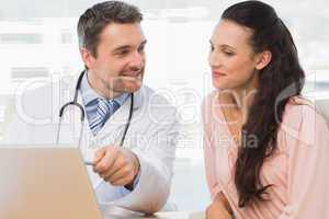 Male doctor showing something on laptop to patient
