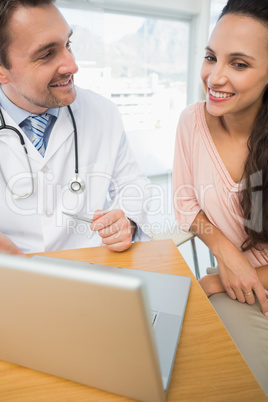 Male doctor showing something on laptop to patient