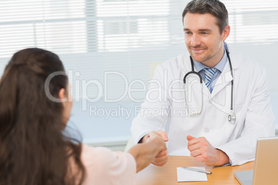 Doctor and patient shaking hands in medical office