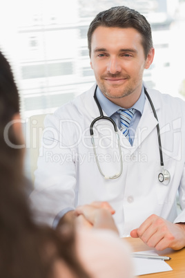 Doctor and patient shaking hands in medical office