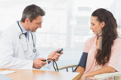 Male doctor checking blood pressure of a woman