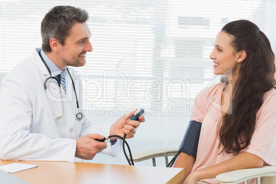 Male doctor checking blood pressure of a young woman